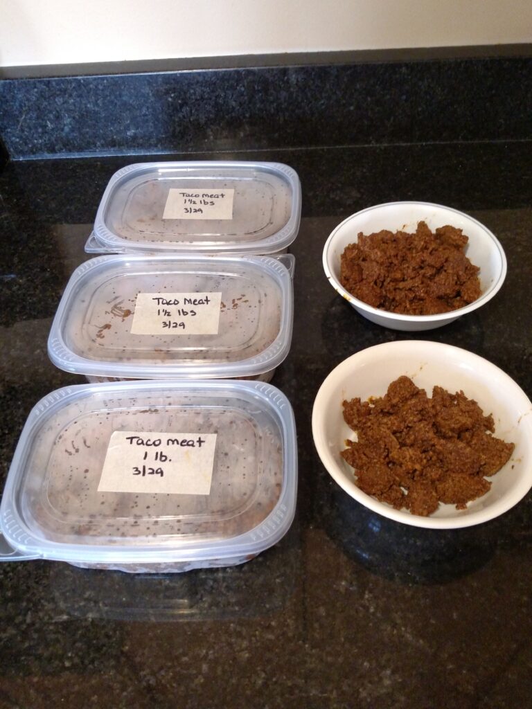 cooked taco meat in 3 containers for the freezer and 2 bowls to eat now