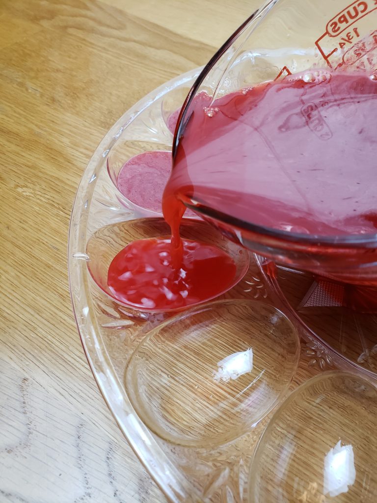 pouring red Jell-O into deviled egg containers