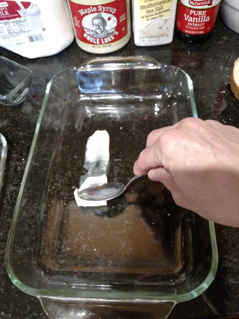 spreading butter in baking pan with back of spoon