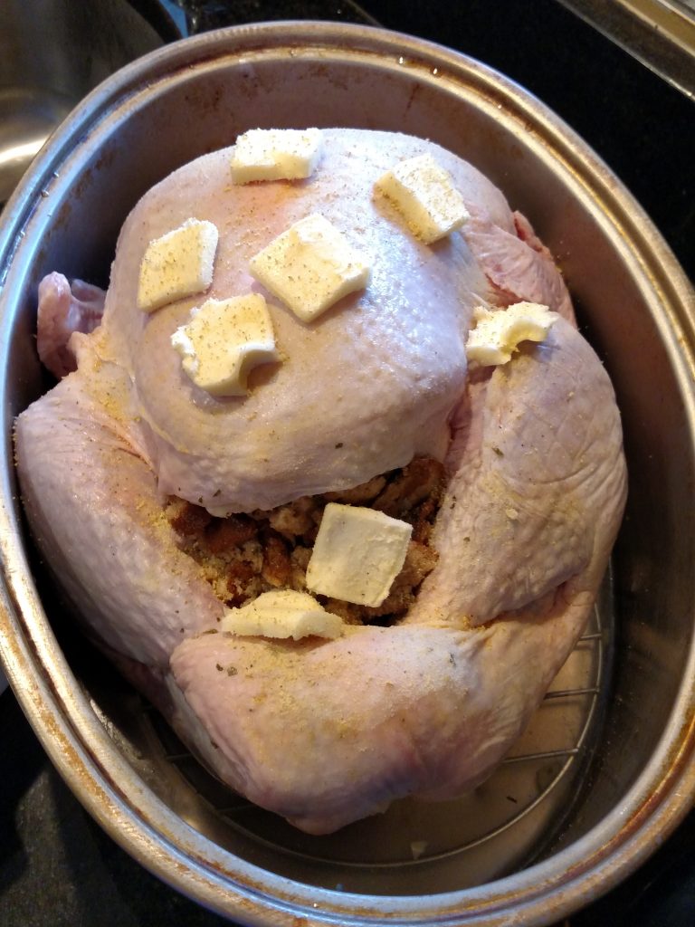 raw turkey ready for oven with butter pats on top