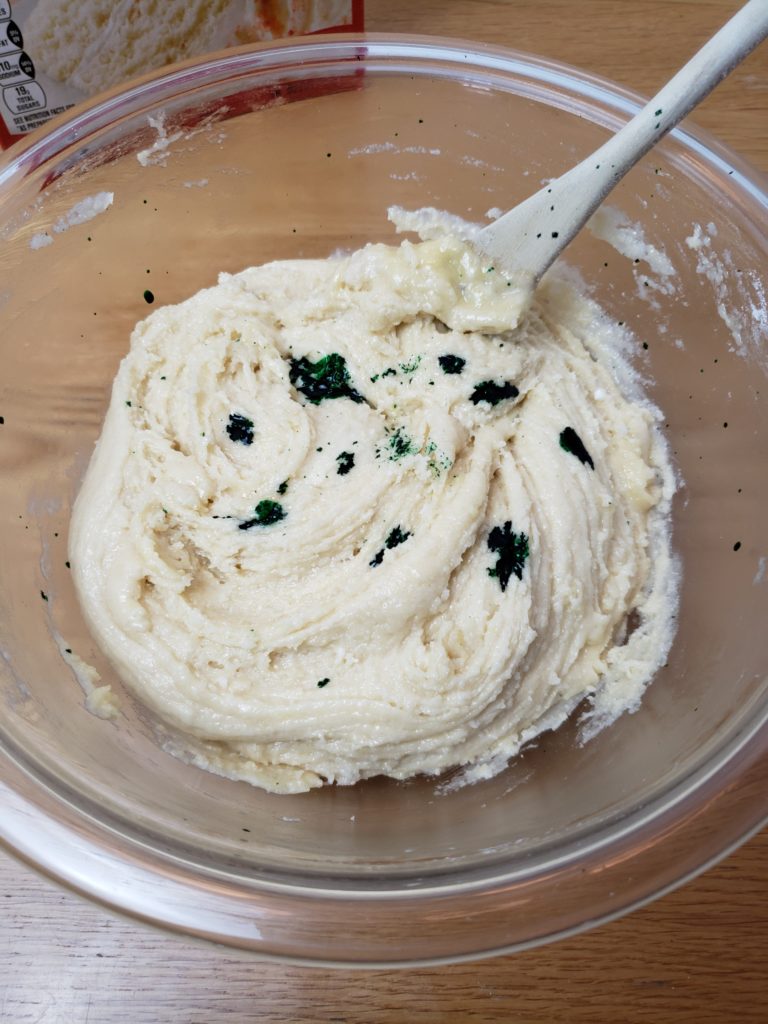 green food coloring drops in white cake batter