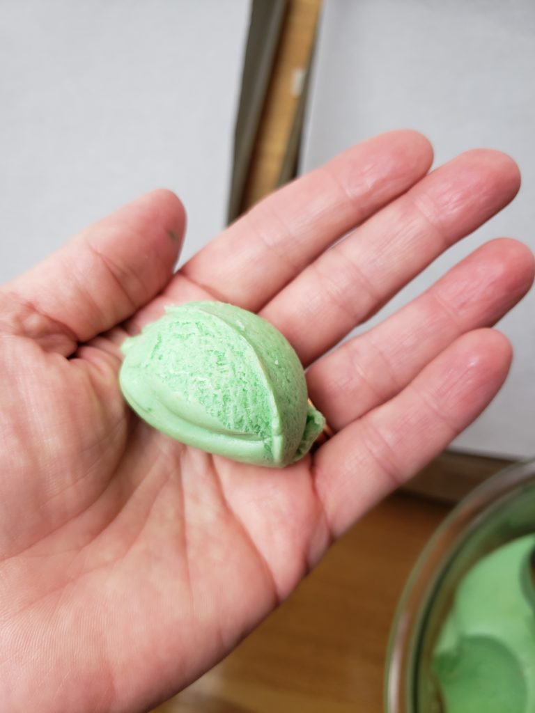 green cookie dough in palm of hand showing size of ball to make