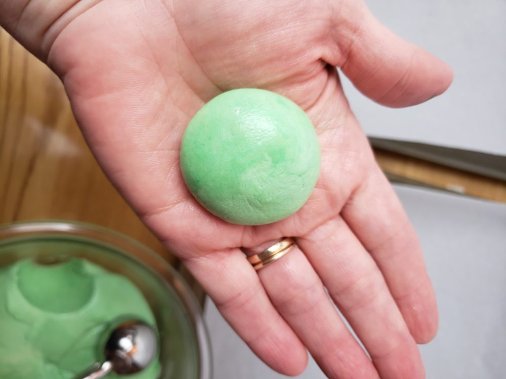 green cookie dough in palm of hand showing size of ball to make