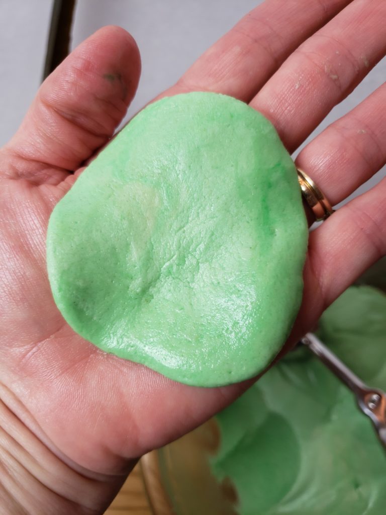 green cookie dough in palm of hand showing how to flatten