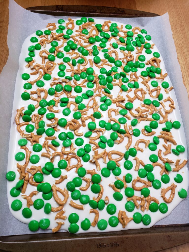 pretzels and green m&m's spread on melted bark