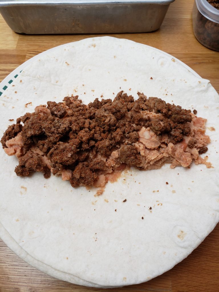 refried beans and meat in enchilada