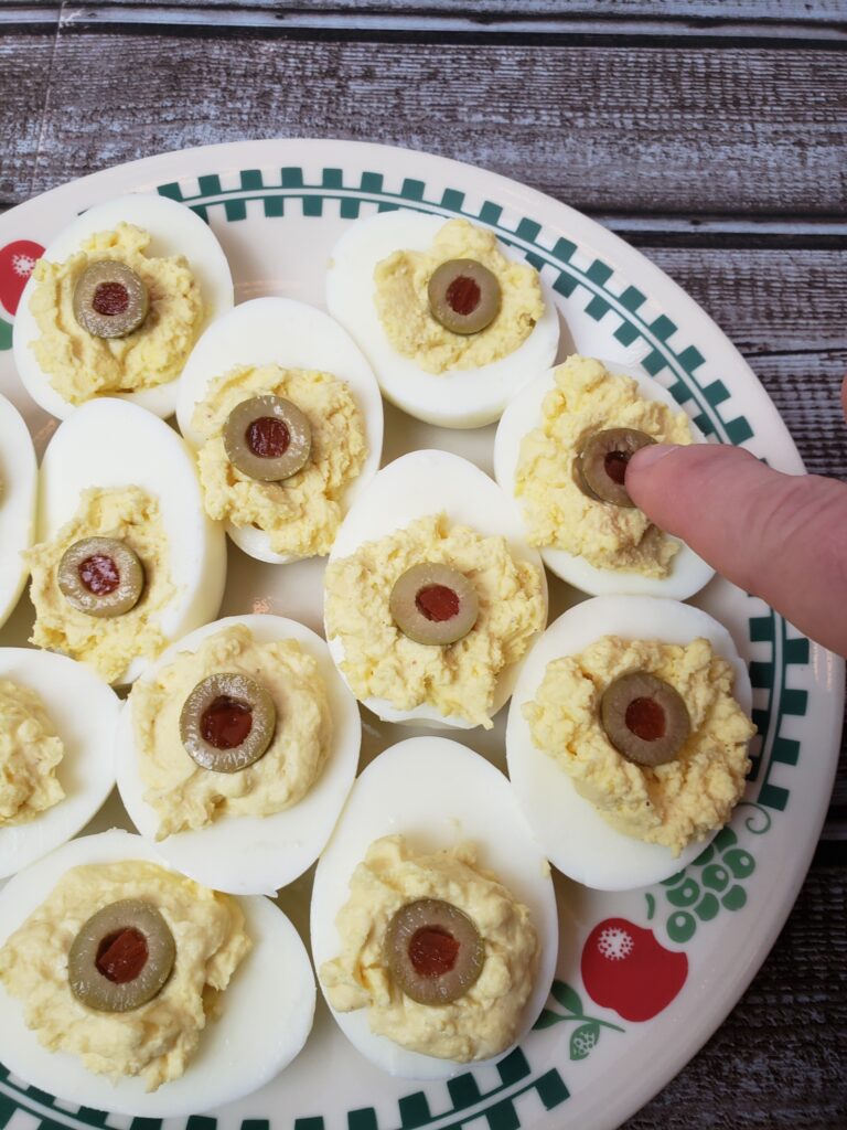 adding half of green olive to deviled eggs.