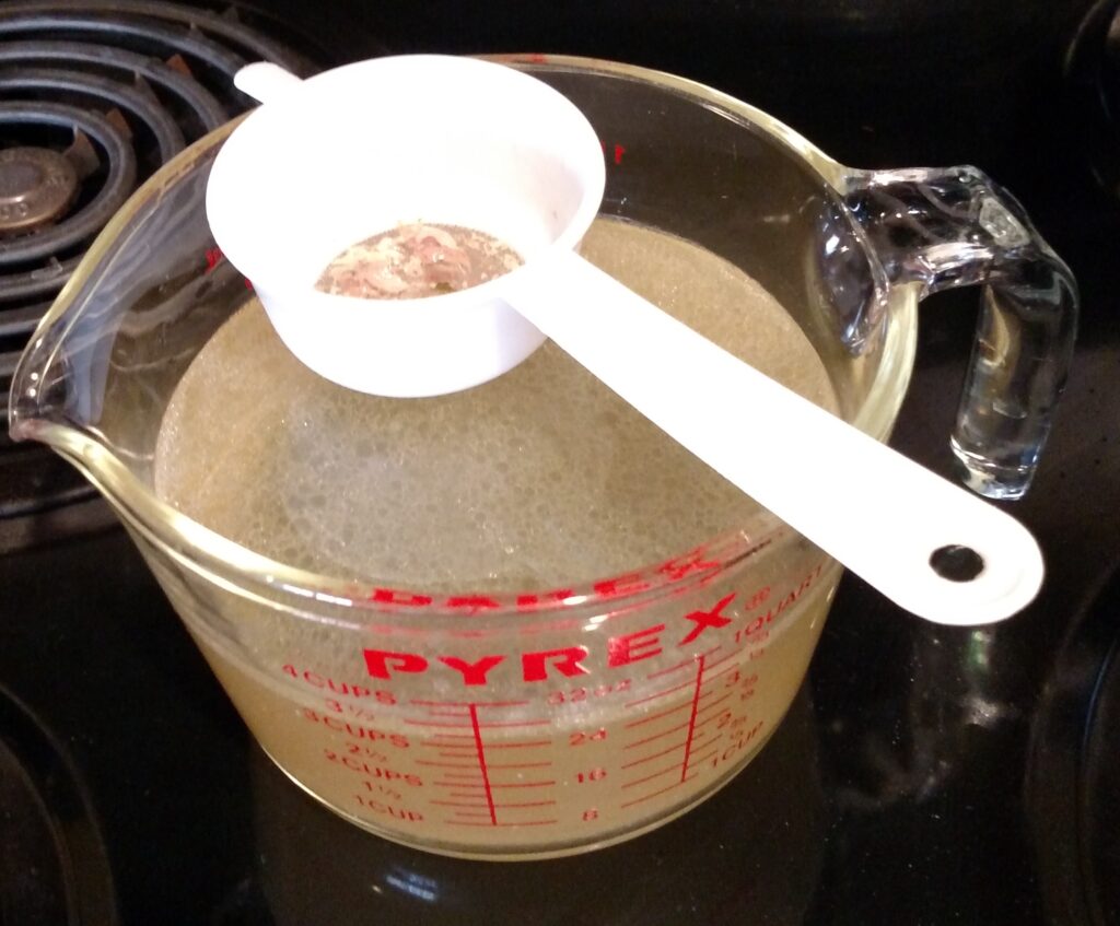 straining turkey broth over pyrex measuring quart