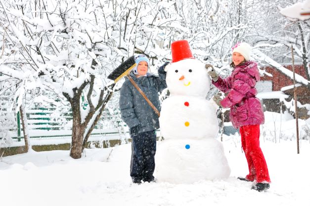 boy and girl with snowman as tall as they are.