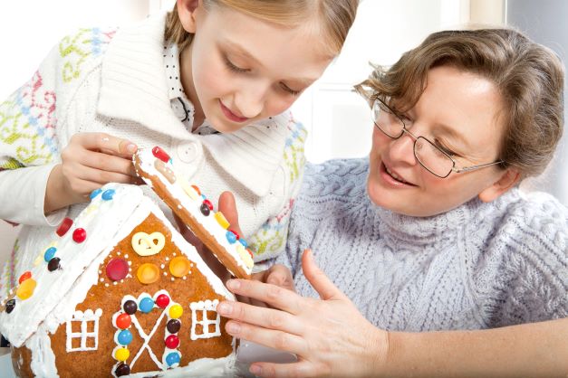 girl and woman putting gingerbread house together.