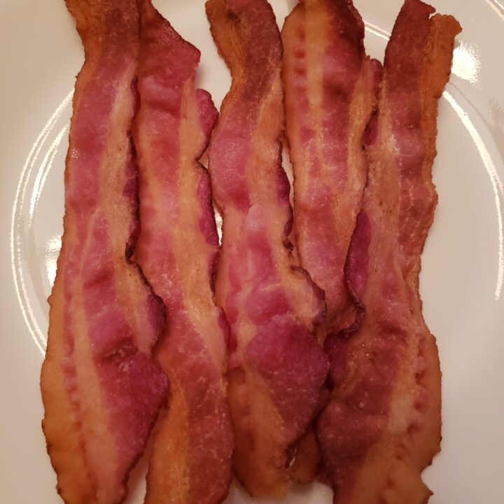 crisp slices of bacon on a white plate.