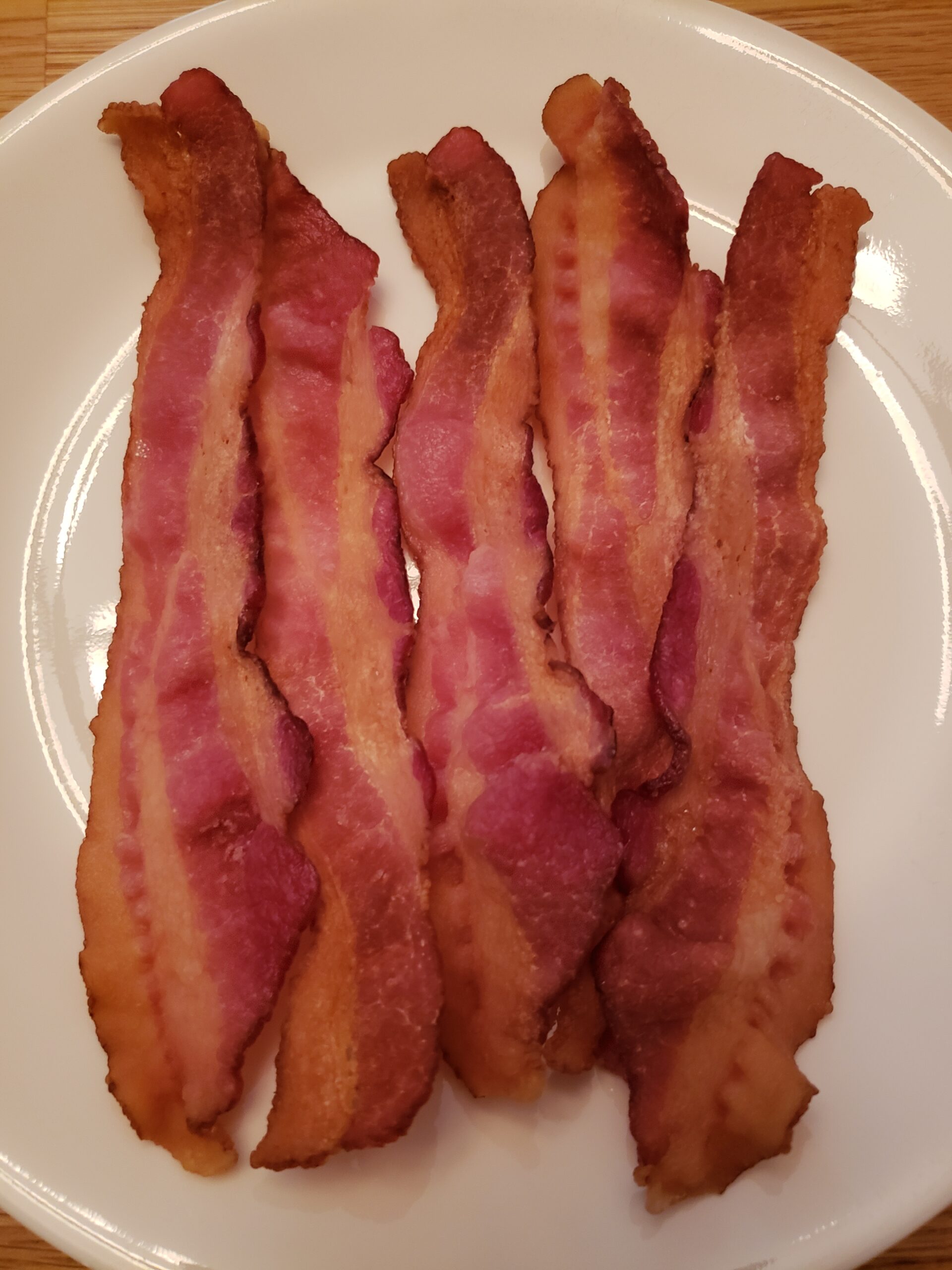 crisp slices of bacon on a white plate.