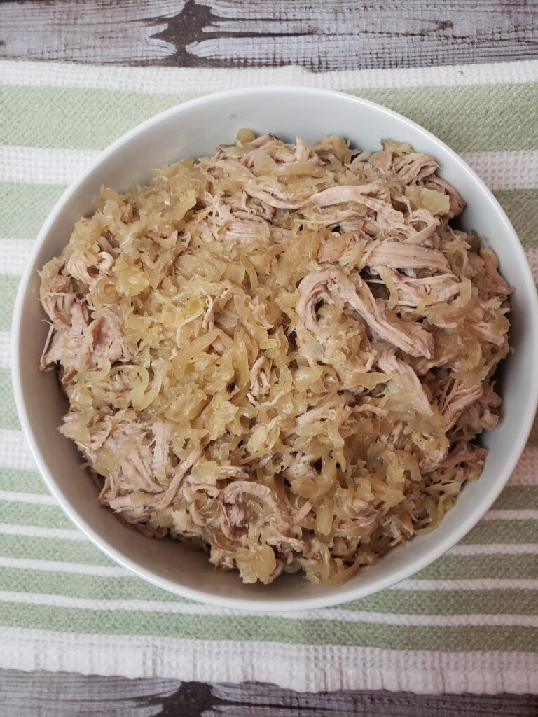 Slow Cooker Pork and Sauerkraut in white serving bowl