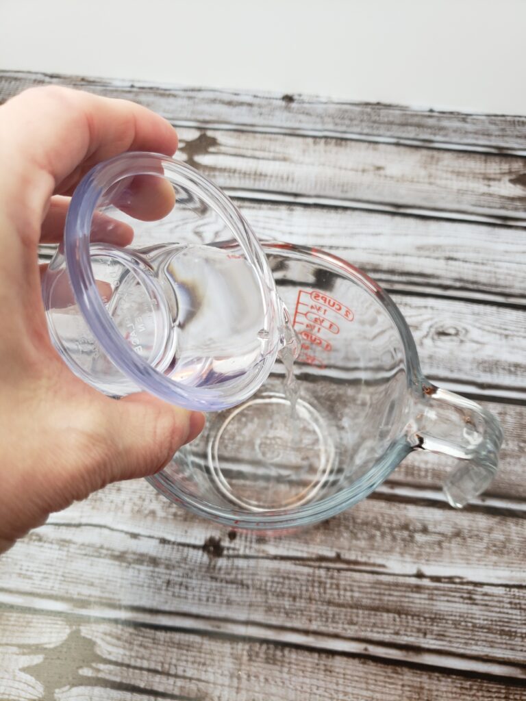 pouring vinegar into glass measuring cup.