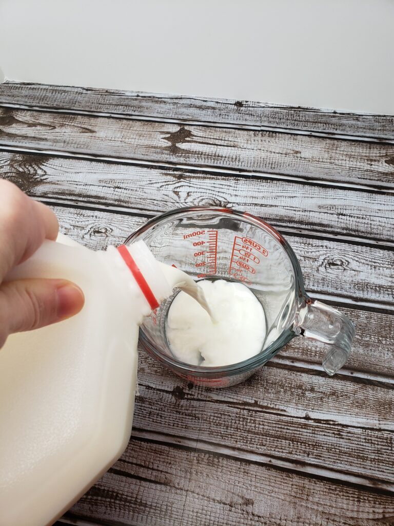 pouring milk into glass measuring cup.