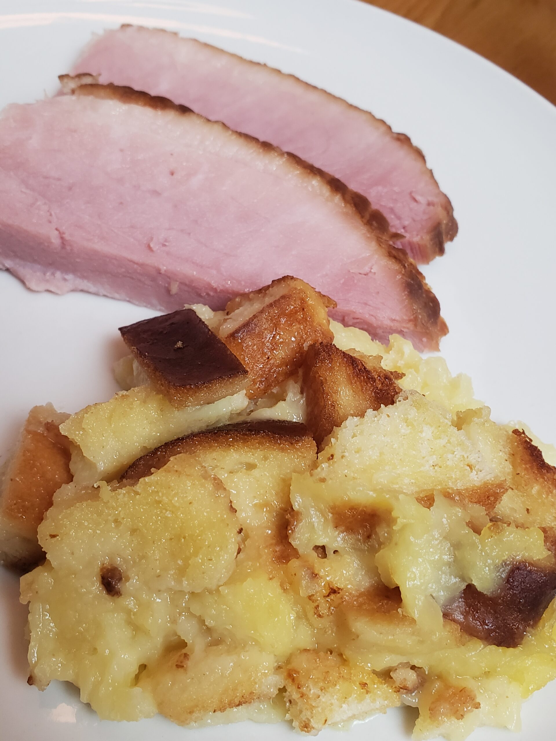 Baked Pineapple Casserole on a plate next to 2 slices of ham