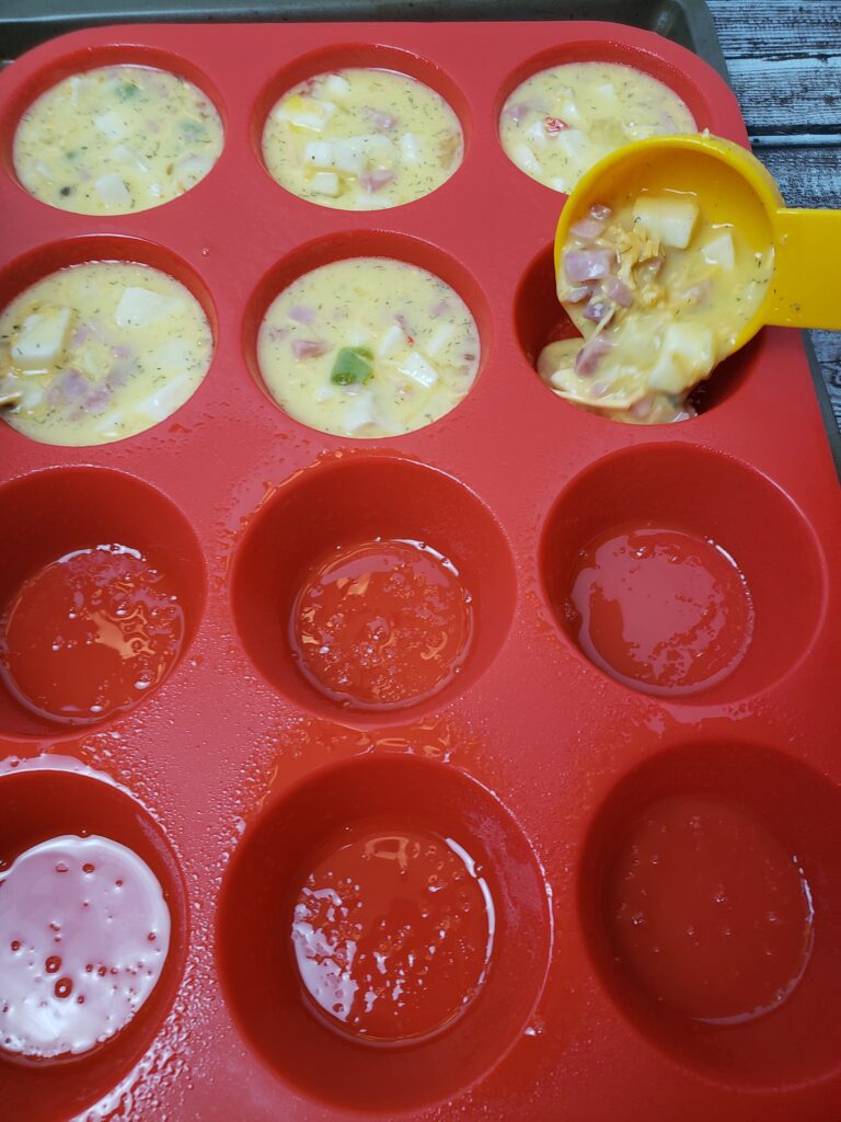 adding egg muffin mixture to muffin wells with measuring cup.