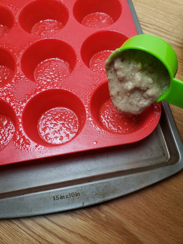 scooping muffin batter into muffin tray with measuring cup.