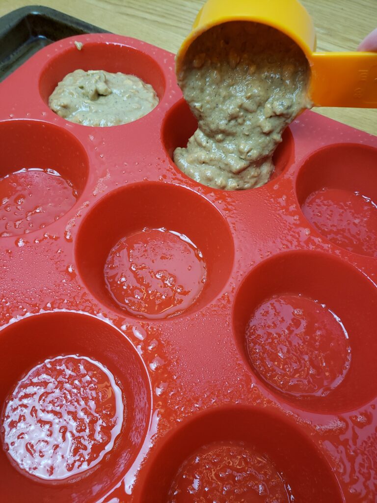 putting muffin batter in the muffin pan with measuring cup.