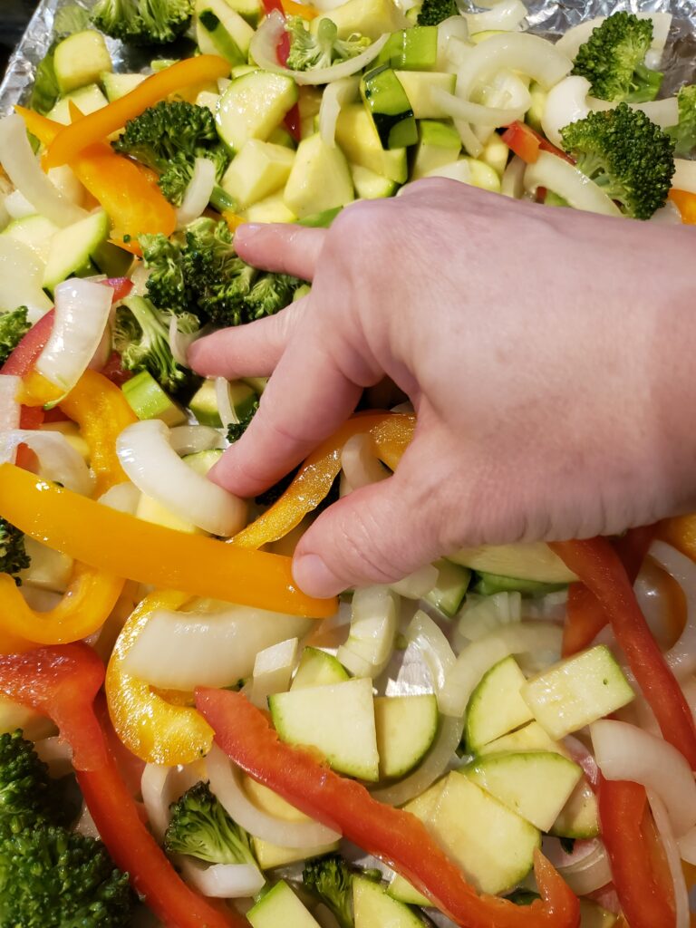 rubbing the oil into the vegetables by hand