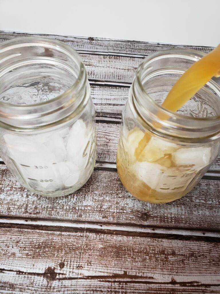 pouring tea over ice cubes in small mason jars.