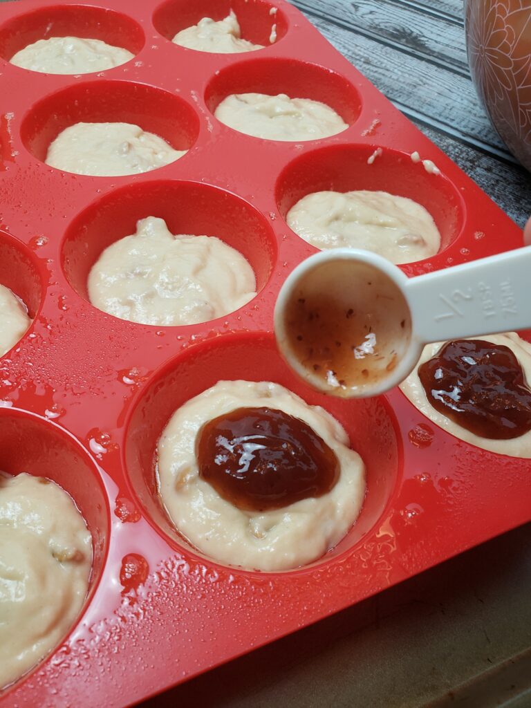 adding jelly to middle of each muffin.