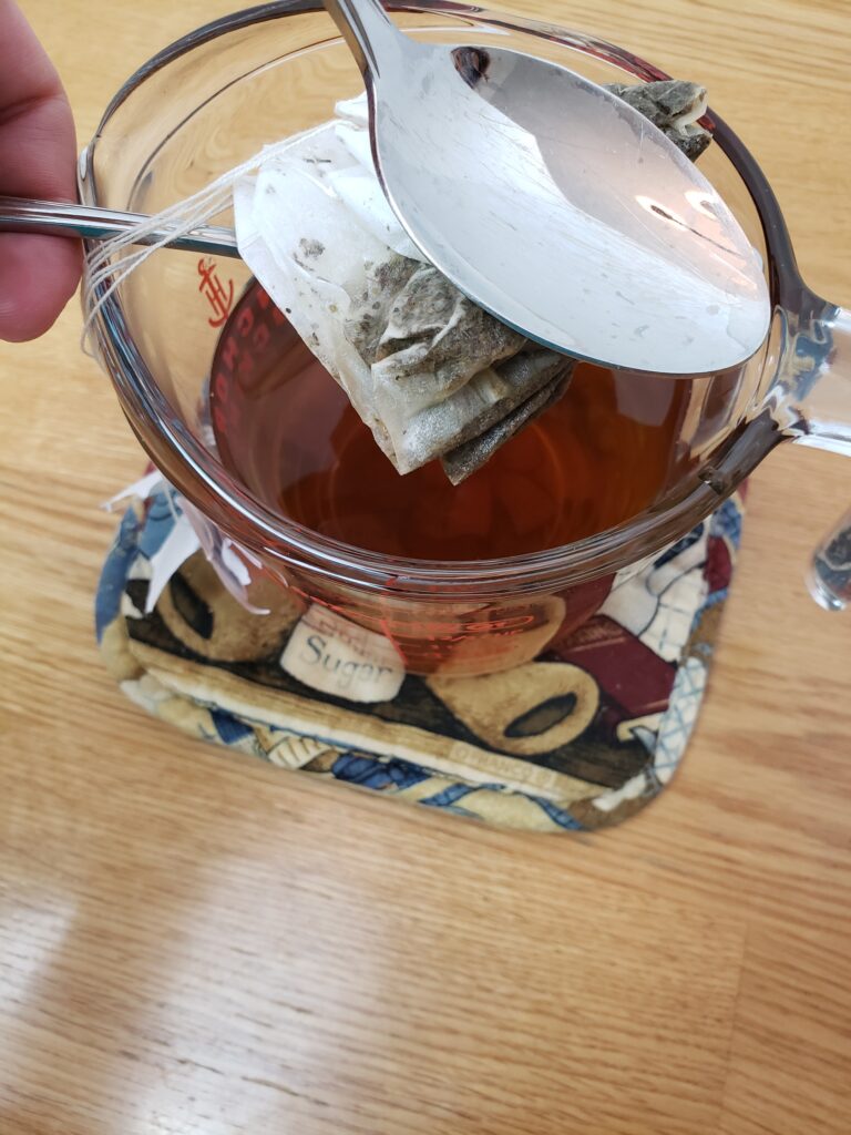 squeezing tea out of tea bags with two spoons.