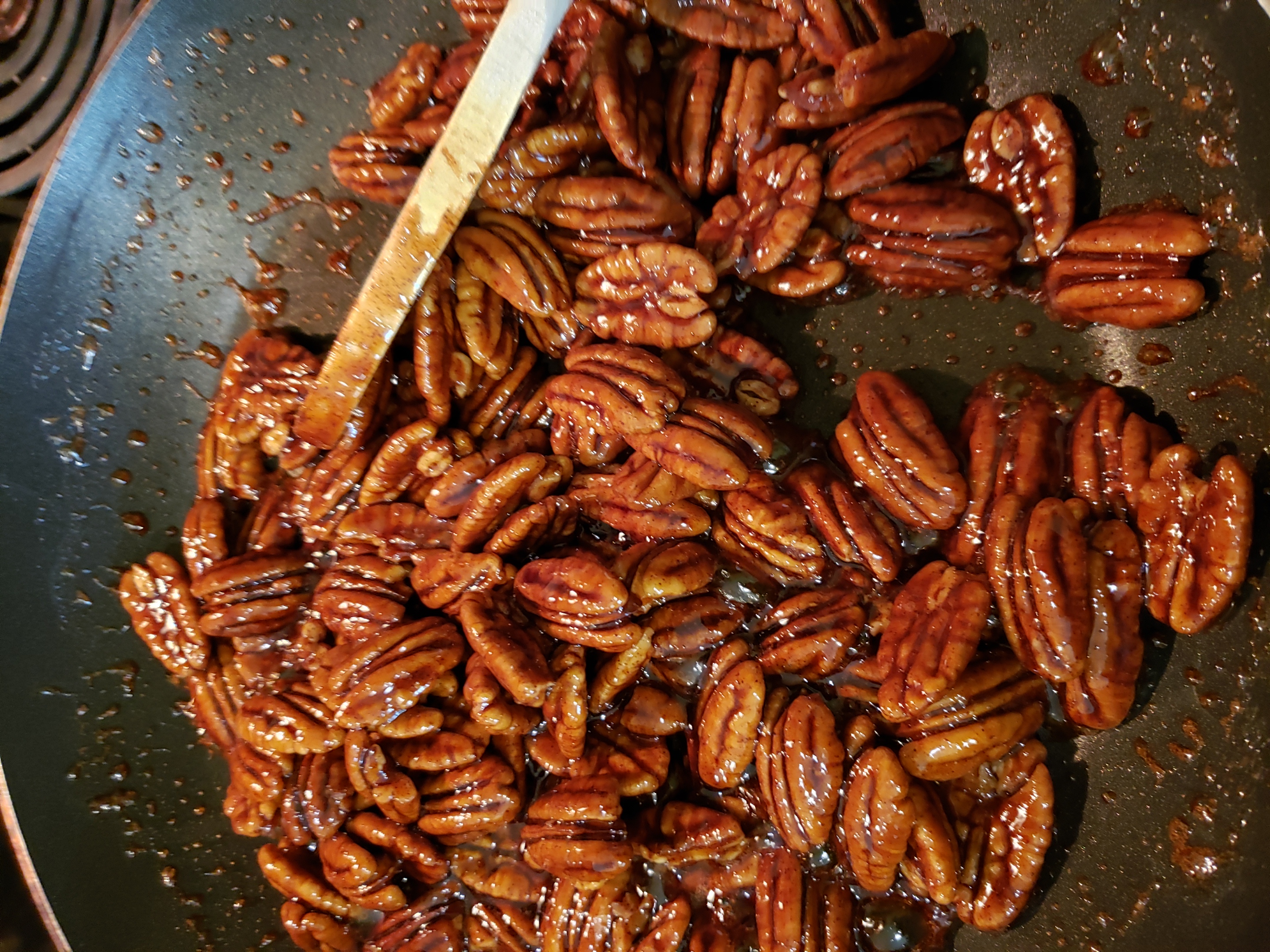 candied pecans in skillet with butter mixture cooked in so they are finished cooking.