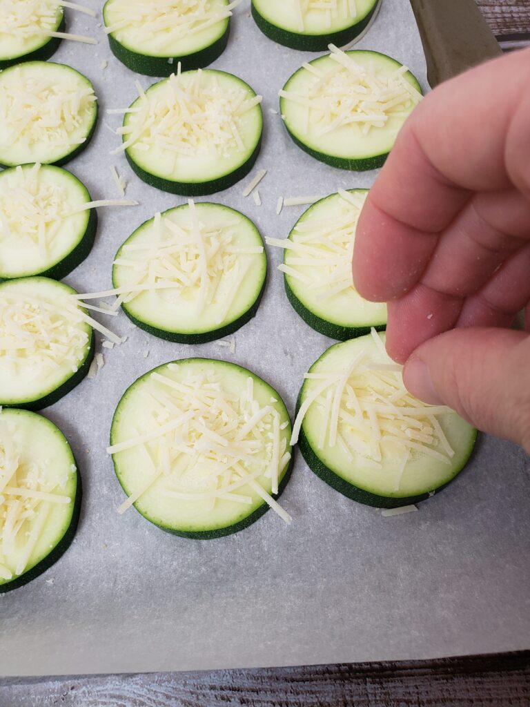 adding cheese to zucchini coins