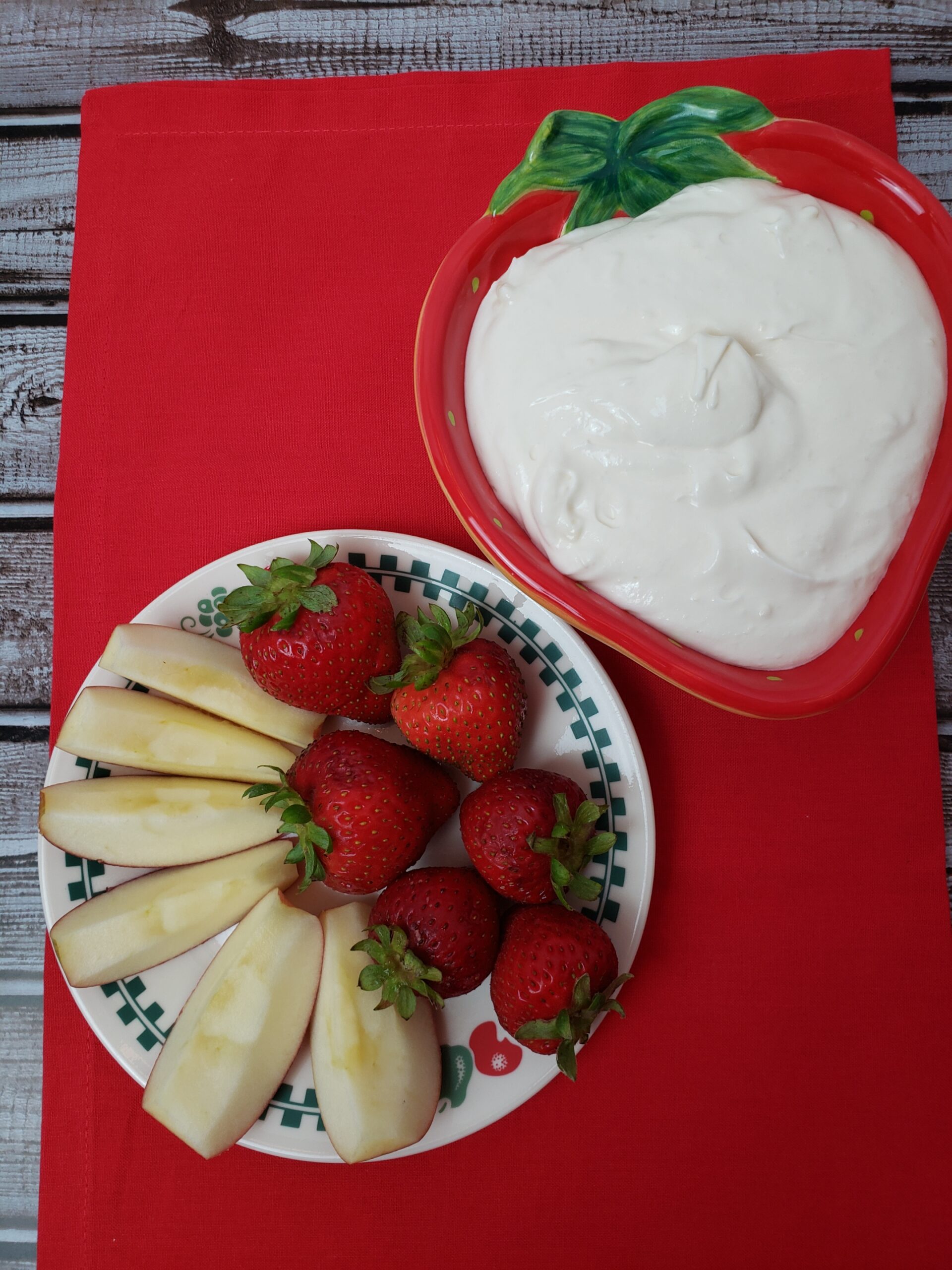 Easy Fruit Dip in strawberry shaped bowl and strawberries and apples on plate next to it.