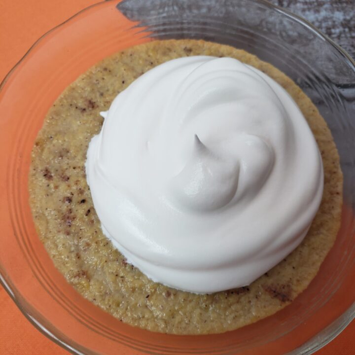 Classic Pumpkin Custard served in clear glass bowl with whipped cream.