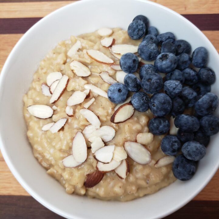 Pumpkin Pie Oatmeal served with sliced almonds and blueberries in a white bowl.