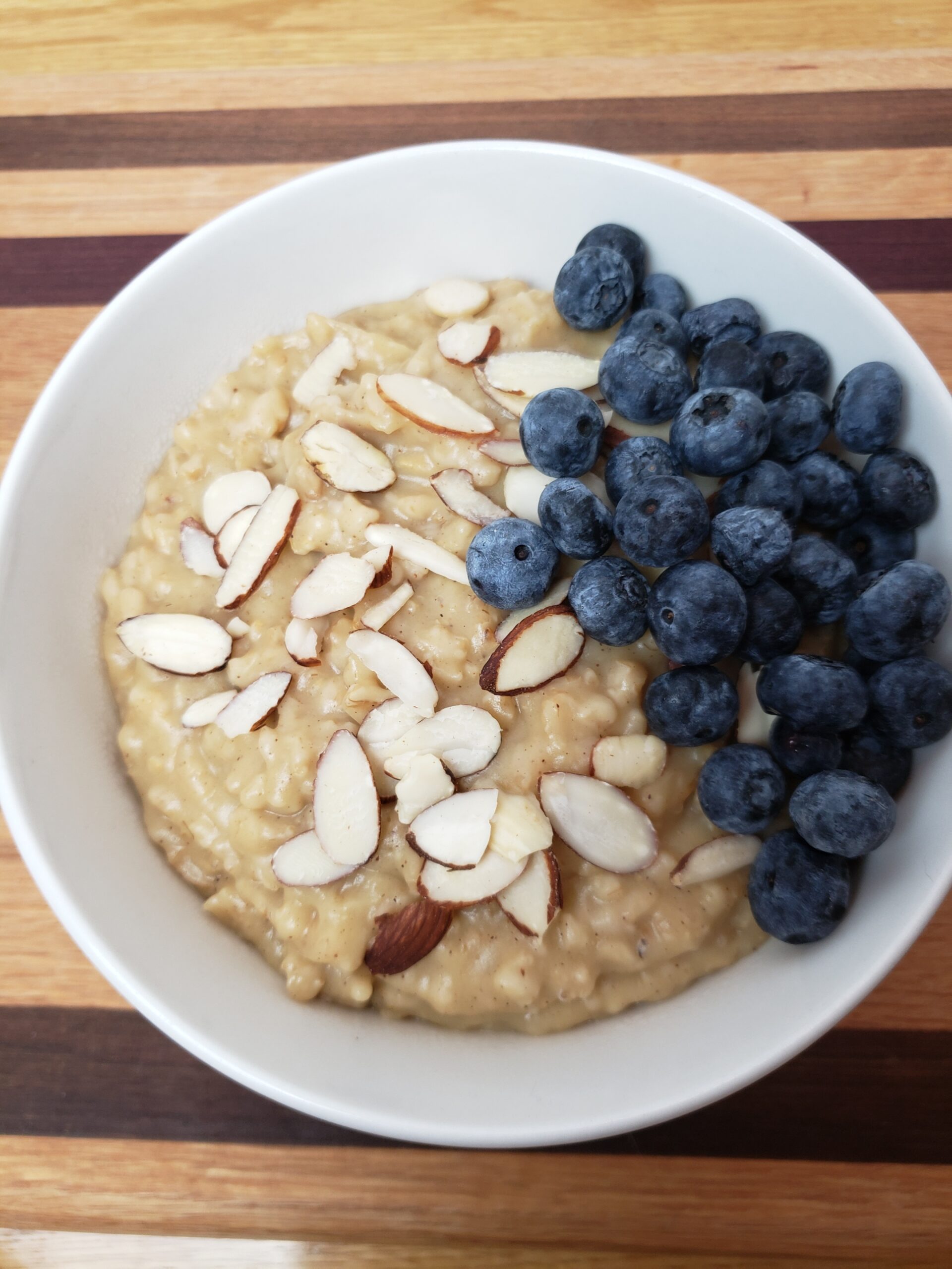 Pumpkin Pie Oatmeal served with sliced almonds and blueberries in a white bowl.