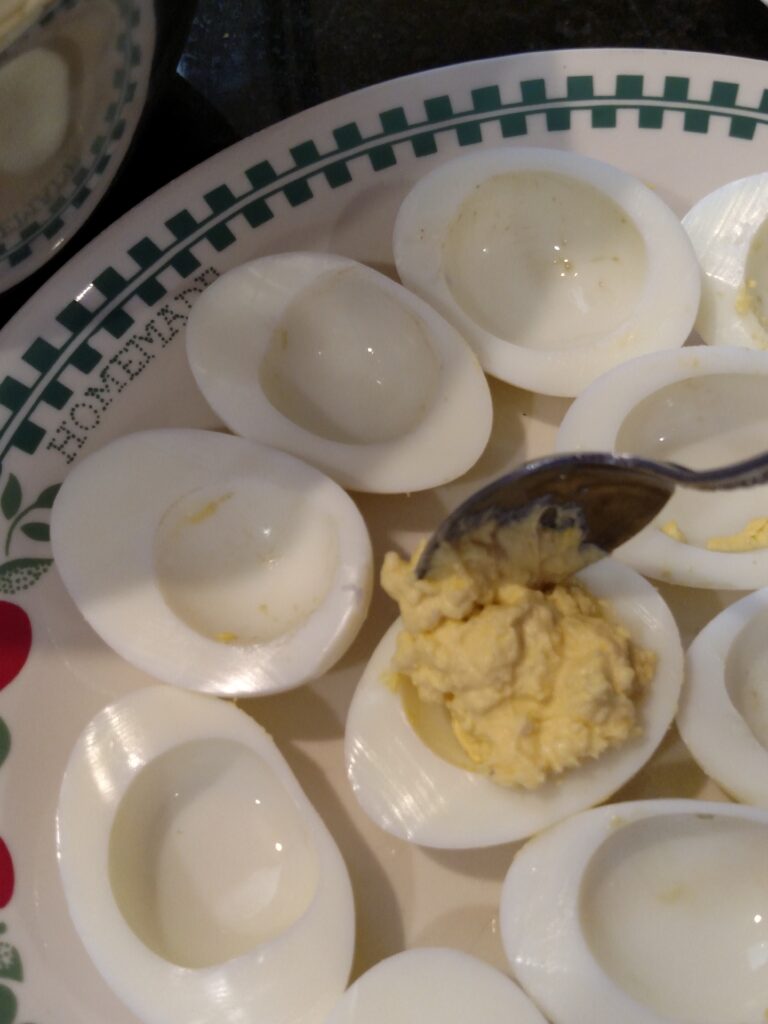 scooping deviled egg filling into egg white halves.