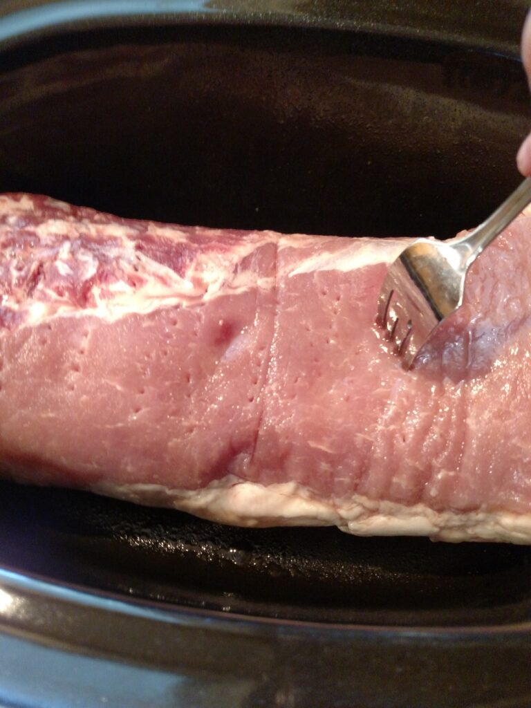 poking pork roast with fork in slow cooker