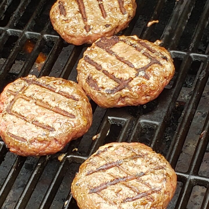 4 cooked hamburgers on the grill