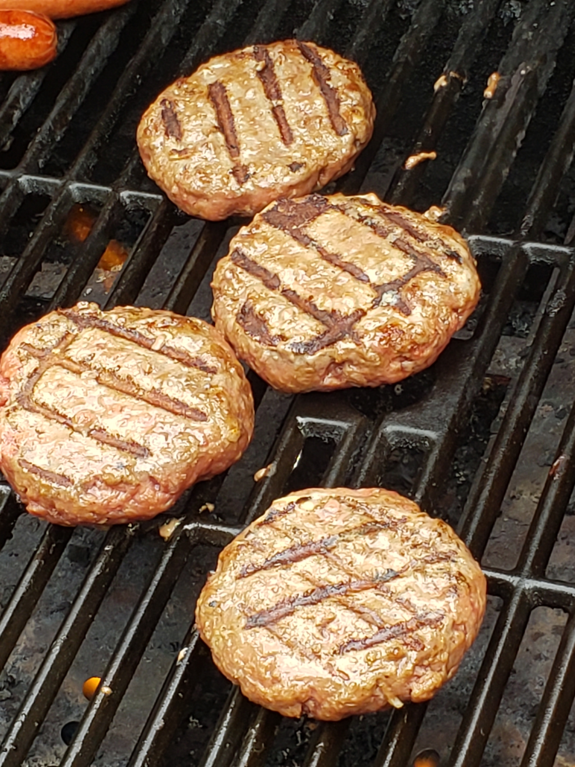 4 cooked hamburgers on the grill