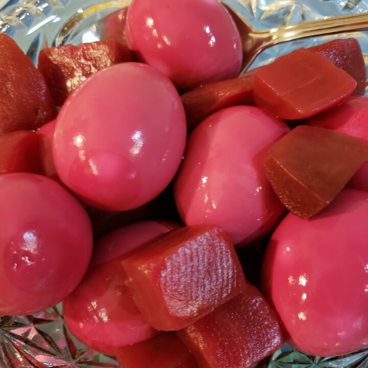 Red Beet Eggs with pieces of beet in a pretty glass dish.