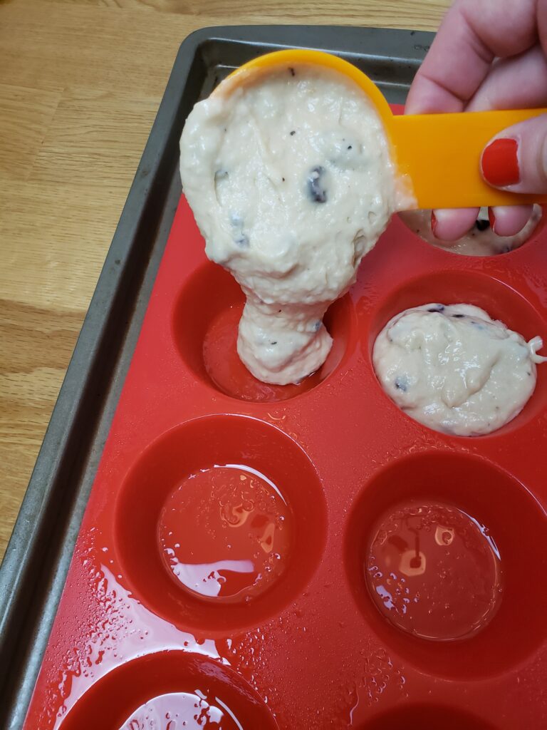 adding batter to silicone muffin pan