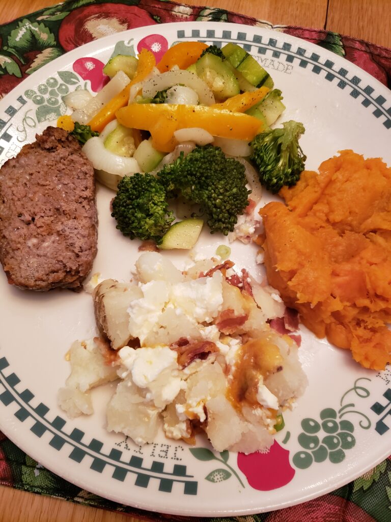 Sweet potatoes on a plate with Oven Roasted Vegetables, Twice Baked Potato Casserole, and Best Gluten Free Low Carb Meatloaf.