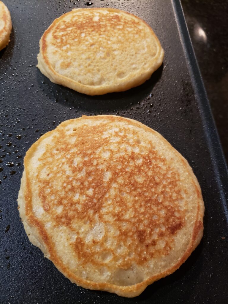 2 beautiful pancakes on griddle almost ready to eat.