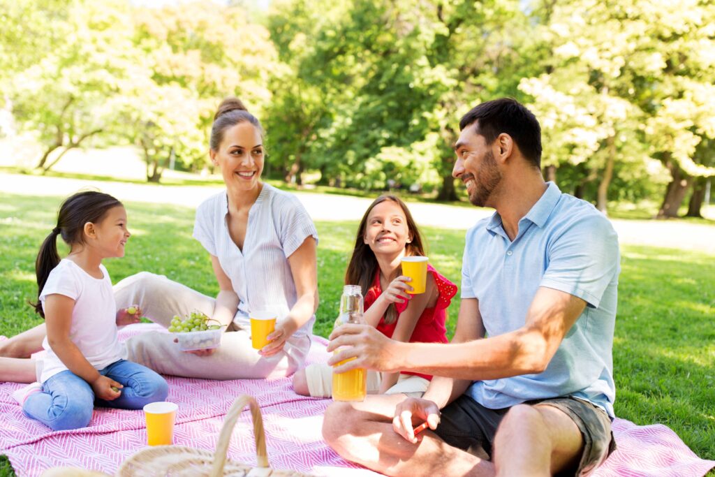 family of four eating on a pink picnic blanket in the shade