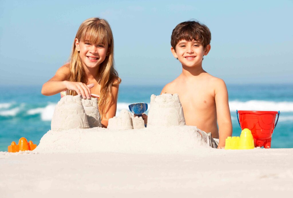 boy and girl making a sandcastle with ocean behind them