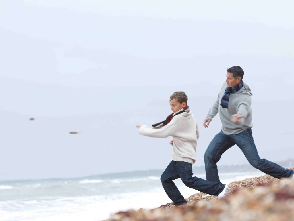 father and middle school aged boy skipping rocks