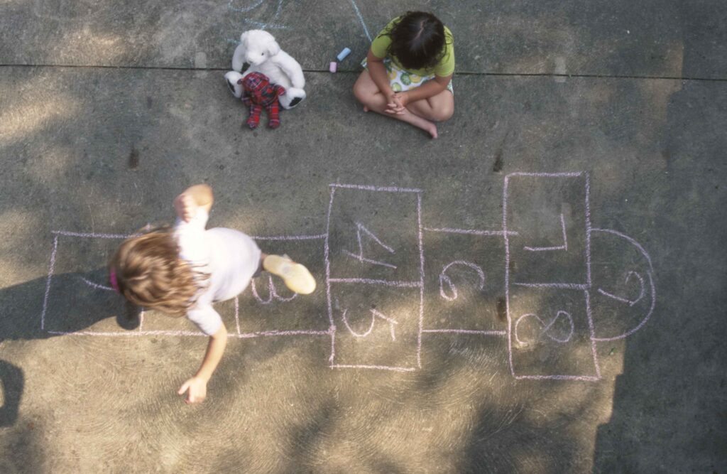 looking down at a girl doing hopscotch and another watching