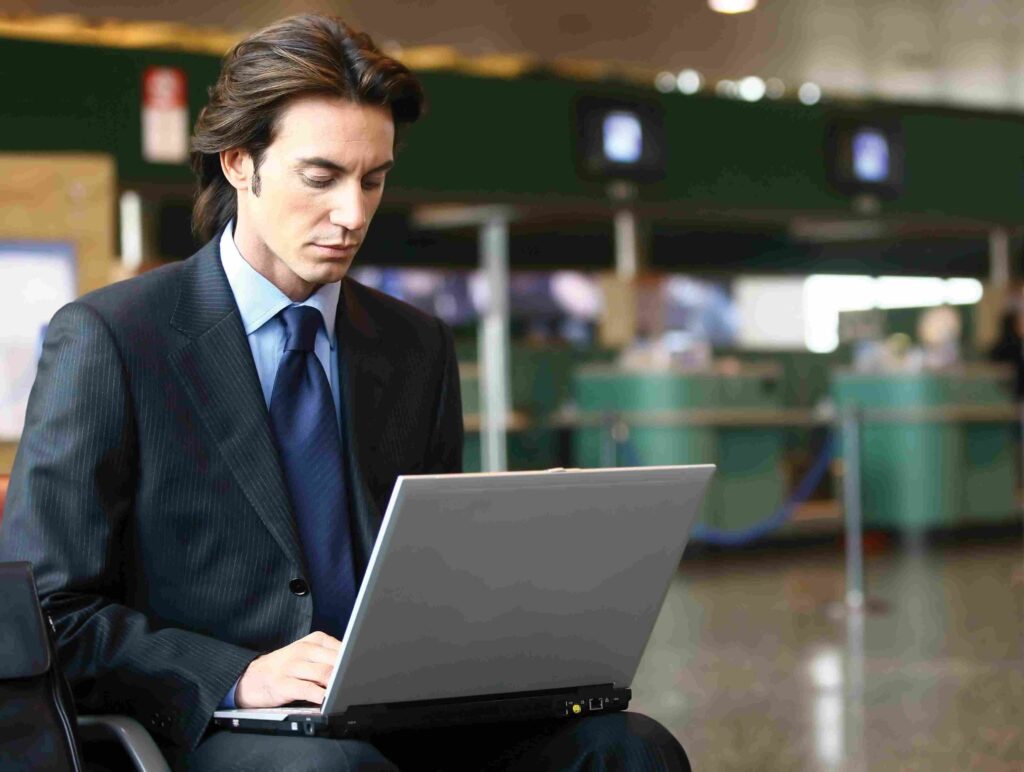 man in suit working on laptop at airport