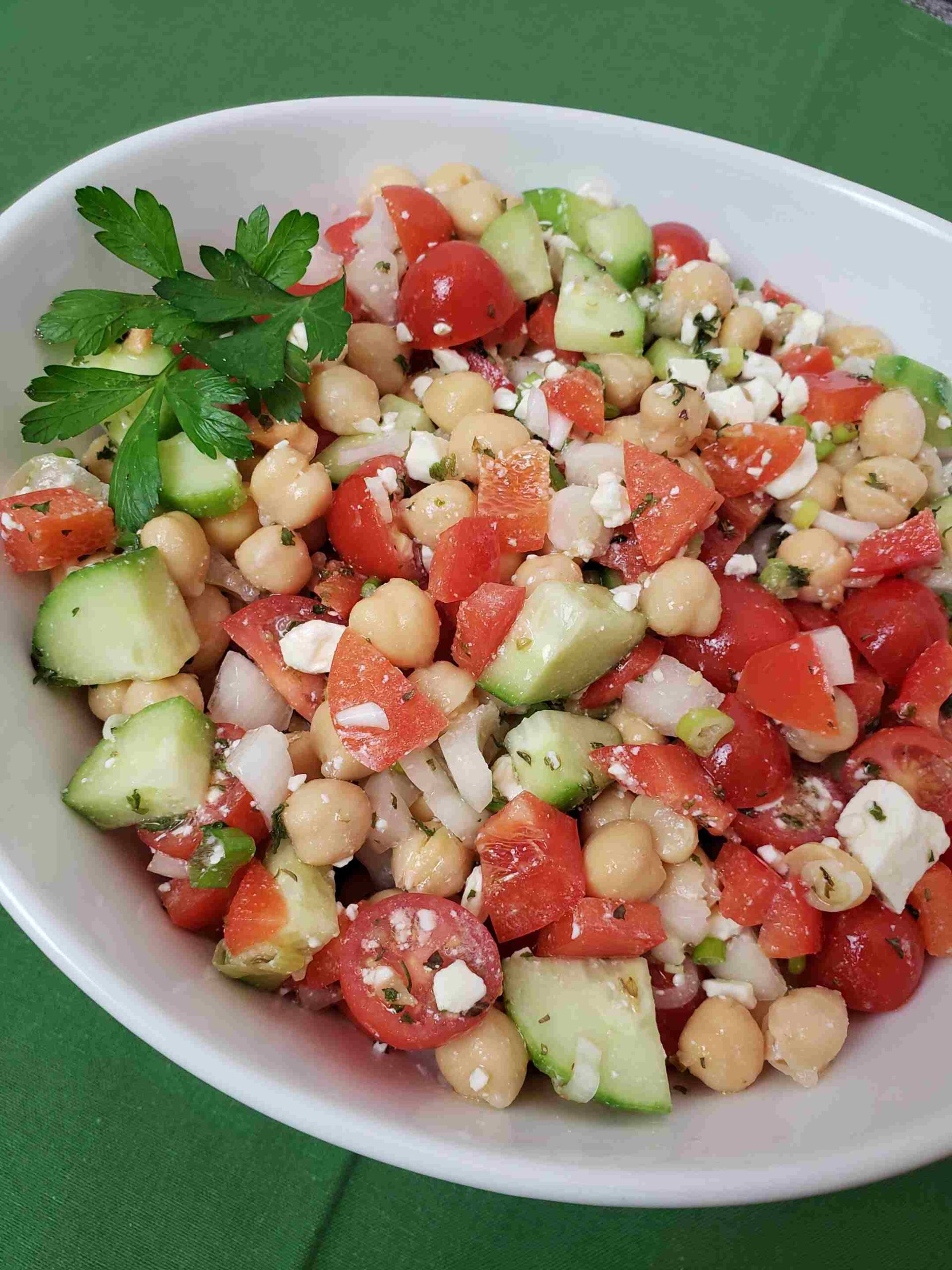 chickpea salad in white bowl on green napkin