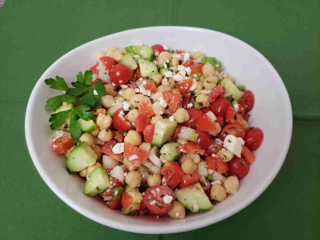 chickpea salad in white serving bowl on green napkin