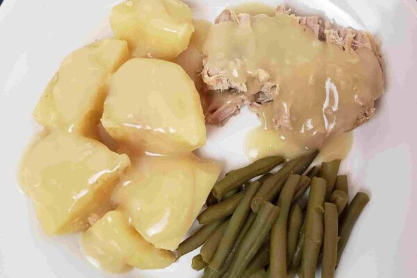 Slow Cooker Pork Roast and Potatoes pork and potatoes with gravy and green beans on white plate