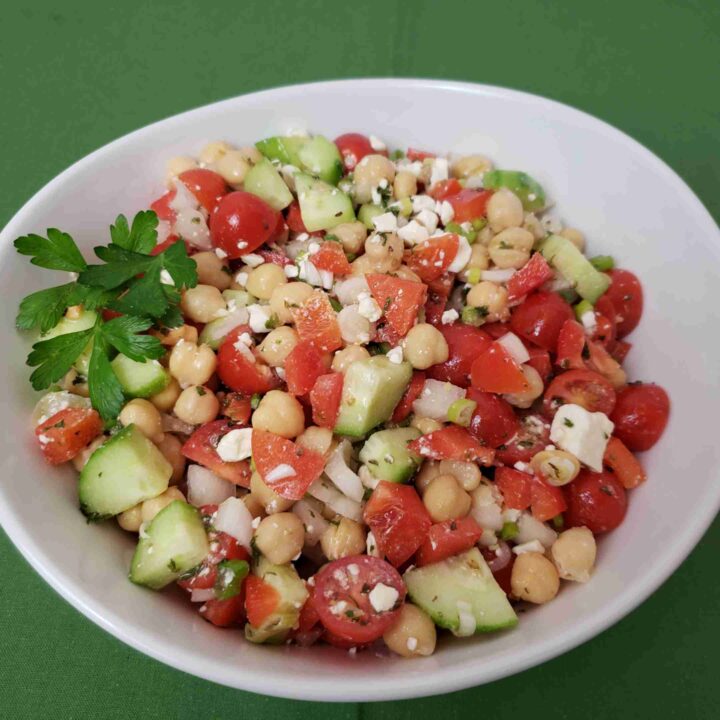 chickpea salad in white serving bowl on green napkin